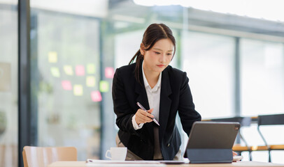 Asian Business woman using calculator and laptop for doing math finance on an office desk, tax, report, accounting, statistics, and analytical research concept
