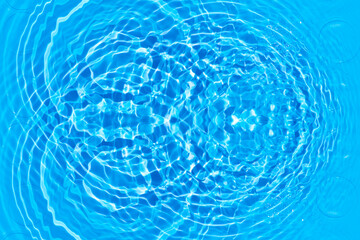 Blue water with ripples on the surface. Defocus blurred transparent blue colored clear calm water surface texture with splashes and bubbles. Water waves with shining pattern texture background.