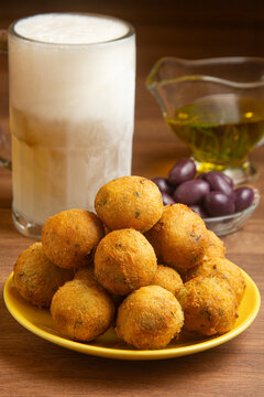 Cod fritters, a frozen mug of draft beer, black olives, and olive oil