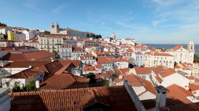 Cinematic view of Lisbon rooftops and historic buildings under blue sky.