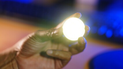Man's fingers holding a glowing coin