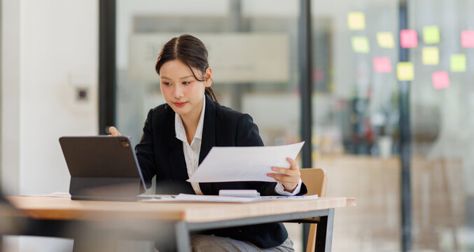Business woman workingon tablet  paper files for searching and checking unfinished document achieves on folders papers at busy work desk office

