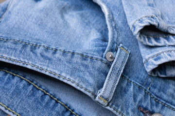 Naklejka premium Blue Denim Jeans Fabric Texture.Close-up of blue denim jeans fabric with visible seams and stitching, showing texture, folds, and worn cotton material detail for fashion or textile concepts.