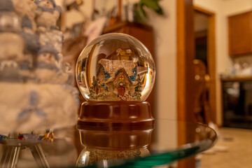 Close up view of a Christmas holiday snow globe with a wooden base, featuring a country church scene