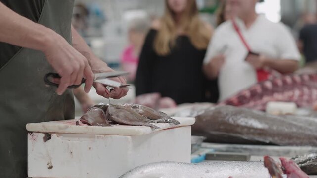 Local fish market showcases fresh seafood being prepared by skilled workers while shoppers browse various catches and enjoy the lively atmosphere.