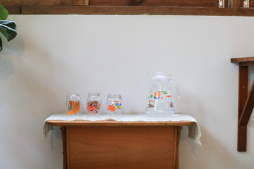 Cute glass and water jar on wooden table Self service in coffee shop. Aesthetic minimal interior decor.