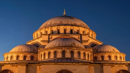 Fototapeta premium Grand Mosque Domes Illuminated at Sunset Against a Deep Blue Sky.