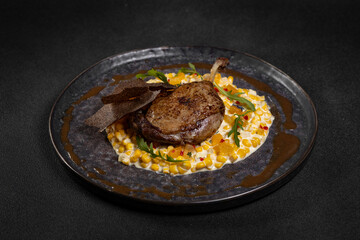 Duck leg with risotto, pumpkin and herbs on a dark background
