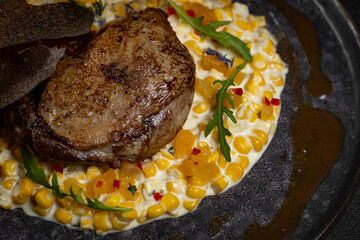 Duck leg with risotto, pumpkin and herbs on a dark background