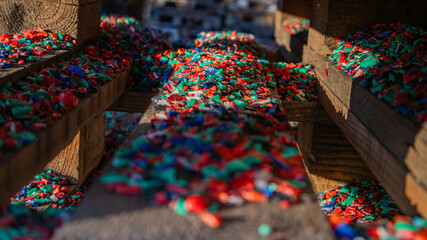 Recycled plastic chips on wooden pallets in sunlight