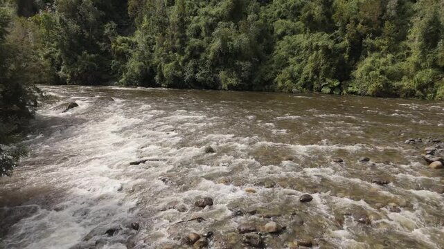 Low Aerial View of Turbulent River Crashing Against Big Boulders
