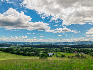 Obraz premium paisaje de naturaleza con un valle verde y un lago bajo un cielo azul con nubes sobre el horizonte de la montaña y el bosque