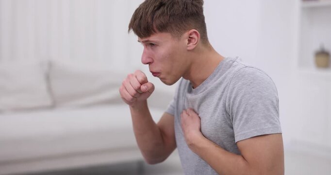 Sick young man coughing at home. Cold symptom