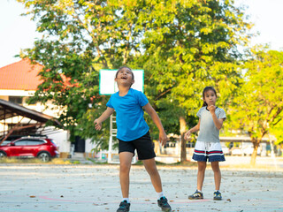Two young girls playing basketball together on outdoor court