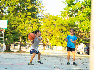 Two young girls playing basketball together on outdoor court