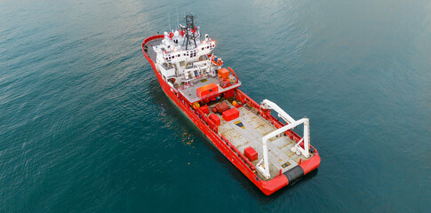 Aerial view of a large red research vessel sailing in the calm blue sea during the day showing maritime transport and industrial exploration concepts and engineering details