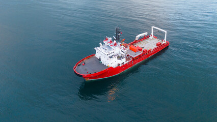 High angle drone view of a red research ship navigating through deep blue waters highlighting the bridge and deck layout suitable for industrial maritime exploration projects © Buğra Kaan Ersoy