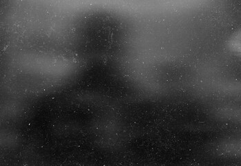 Obraz premium Monochrome silhouette of an adult figure seen through a speckled glass surface, creating a moody urban night scene full of mystery, introspection, and cinematic atmosphere