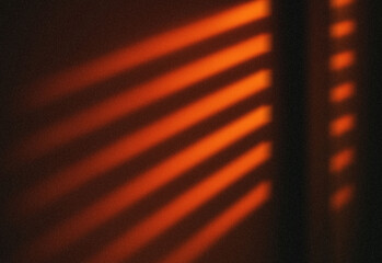 Abstract warm red light patterns cast through window blinds at dusk, forming diagonal stripes and a moody cinematic atmosphere ideal for creative projects and striking backgrounds.