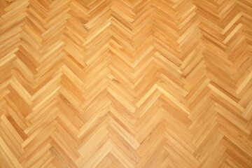 A close-up view of a wooden herringbone patterned floor, showcasing the intricate arrangement of light-colored wood.