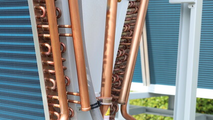 Copper tube for air conditioners. Close-up of the copper pipe on the edge of the aluminum panel cooling the air conditioner's refrigerant with selective focus.