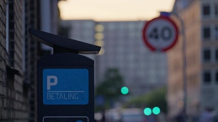Parking meter displaying ''Betaling'' meaning payment in a city street scene at sunset. Copenhagen, Denmark
