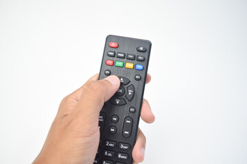 Human hand holding and pressing a black TV remote control isolated on white background