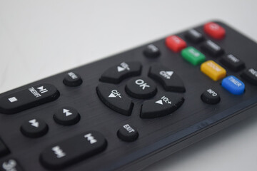 Close-up macro shot of a black television remote control showing various buttons and textures