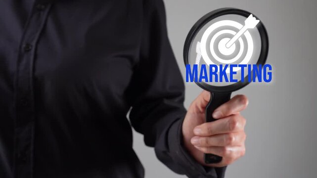 Marketing objective analysis. Close-up of a woman's hand with a magnifying glass analyzing a target icon with the word "marketing".