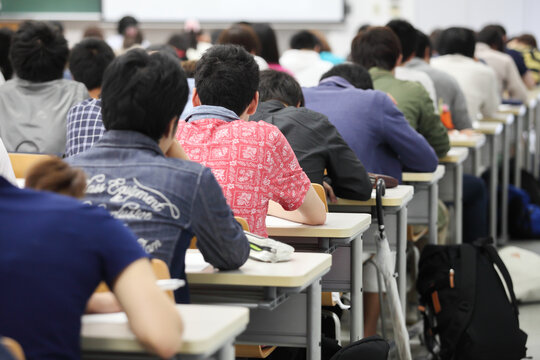 日本の大学の大教室で机に並んで勉強する男子学生の後ろ姿 キャンパスライフ 教育　大学生のイメージ