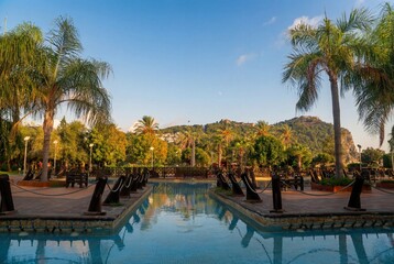 Public park with lush green trees and flowers against the backdrop of Alanya Castle, Turkey....