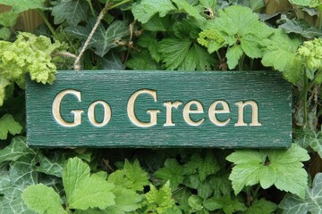 Sign promoting environmental awareness placed among green plants in a garden setting during daytime