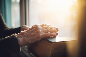 Hands resting on an open book by a window during the late afternoon with sunlight pouring in