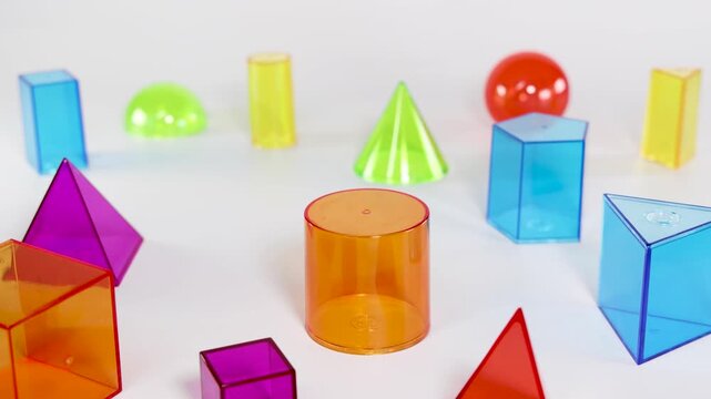 Hand Placing Colorful Geometric Solids on White Surface for Education