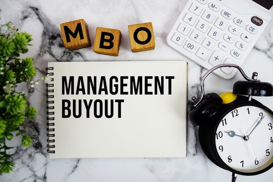 MBO Management Buyout text with calculator and alarm clock on marble background