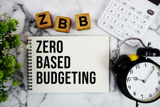 ZBB Zero Based Budgeting text with calculator and alarm clock on marble background