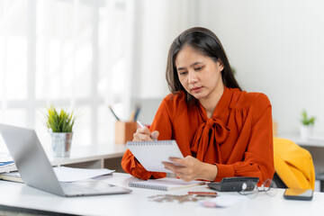 Diligent Determination: An focused individual engrossed in meticulous planning, recording essential data in a notebook amidst a productive workspace.