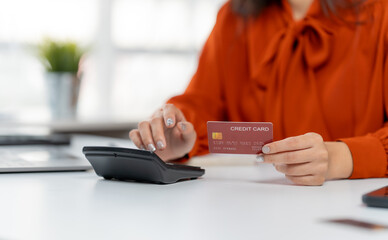 Financial transaction with credit card: Focused on the hands of a person, calculating expenses using a calculator. Featuring a credit card representing modern financial processes.