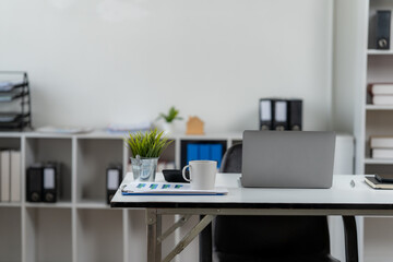 Modern Workspace Setup: A minimalistic office desk setup features a laptop, essential office supplies, and a touch of greenery, signifying a productive and organized work environment.