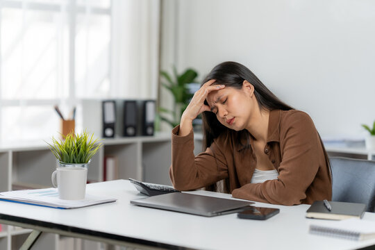 Overwhelmed in the Office: A professional experiences a moment of stress while working, hand on head, in her office. Evoking emotions of fatigue and job pressure.