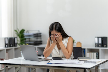 Tired worker at Desk: In a brightly lit office, a young woman is shown at her desk with a visible display of weariness, her hands covering her face, conveying the pressures of work
