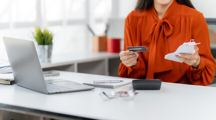 Streamlined Transaction: A woman effortlessly manages financial tasks, paying bills with a credit card while analyzing paperwork in a bright, modern setting.