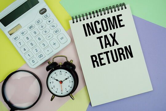 Income Tax Return text with calculator, alarm clock and magnifying glass