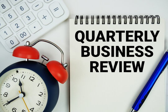 Quarterly Business Review (QBR) text written on notepad with alarm clock and calculator on white background