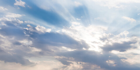 Obraz premium Radiant sky with powerful sunbeams bursting through layered clouds, casting streams of light across soft blue and gray tones, creating an inspiring, dramatic, and hopeful celestial scene