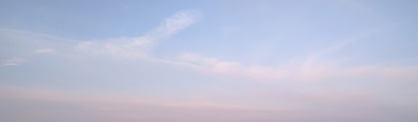 Soft pastel evening sky with faint pink and lavender streaks brushing across pale blue, creating a...