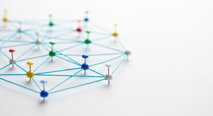 A network of colorful push pins are intricately connected by blue threads against a clean white background, symbolizing communication and interconnected systems.