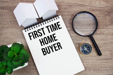 First TIme Home Buyer text written notepad with house model, magnifying glass and compass on wooden background