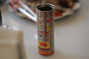 Metal thermos tube with various inscriptions standing on a table, minimal composition with everyday lifestyle and travel concept