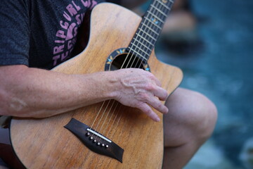Hand playing a wooden classical guitar, close-up view with warm natural light and focus on strings and fingers
